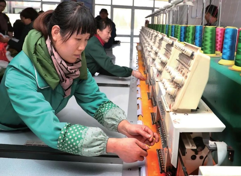 陇县关山文化旅游产品开发有限公司的职工在刺绣纺织生产线上工作.jpeg